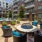 a patio with chairs and tables and a fountain in front of a building